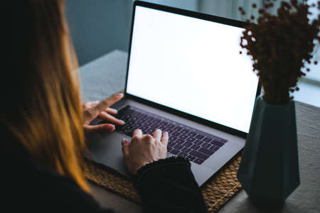 Young woman use laptop computer with white blank screen, mockup, typing text on the keyboard.の写真素材