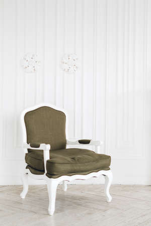 Comfortable vintage armchair in bright living room with minimalist interior and white walls.の写真素材