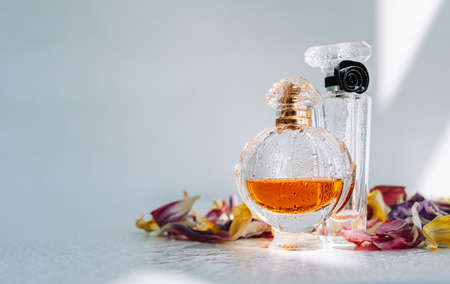 Perfume bottles with fresh water drops on white background with dried colorful flowers petals.の写真素材
