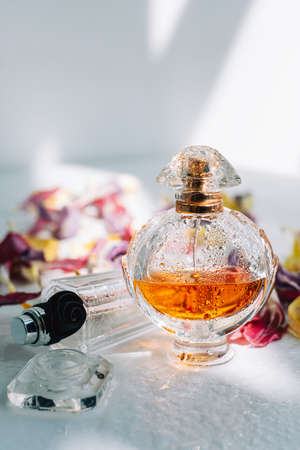 Perfume bottles with fresh water drops on white background with dried colorful flowers petals.の写真素材