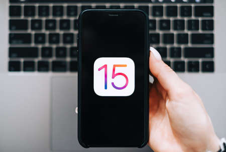 iPhone with iOS 15 logo on the screen close up, new operating system 2021 on apple devices.