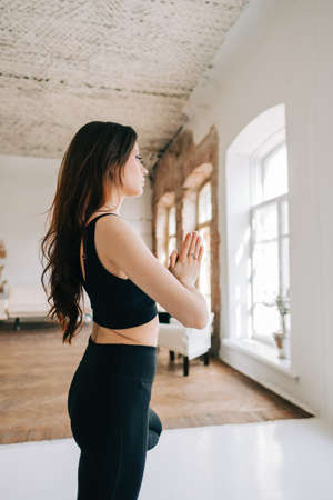 Beautiful brunette fitness woman meditate, doing yoga indoors at home. Staying fit and healthyの写真素材