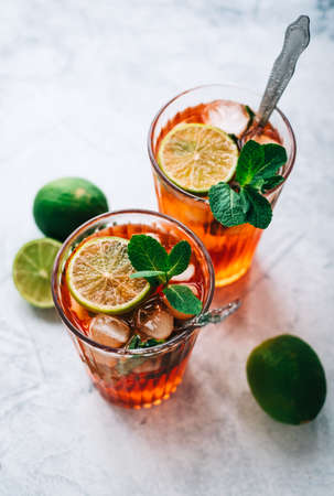 Fresh cocktail, lemonade with lime, mint and pieces of ice on a white table.