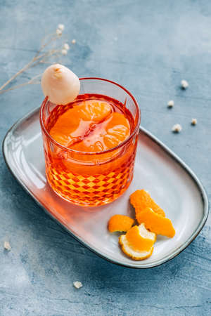 Fresh cocktail in glass with orange juice on blue background. Negroni with orange peel on a plate.の写真素材