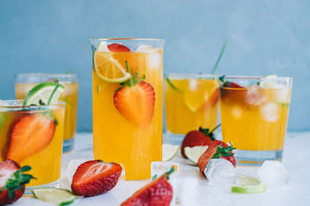 Fresh orange strawberry mojito in different glasses with ice cubes and slices of lime on the table. Summer refreshing drinkの写真素材