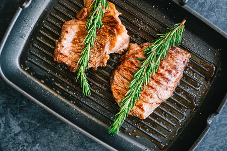 Grilled buffalo beef steak with rosemary in black grill pan on the table.の写真素材