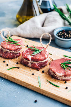 Raw beef filet mignon steak on a wooden board with rosemary and spices.の写真素材