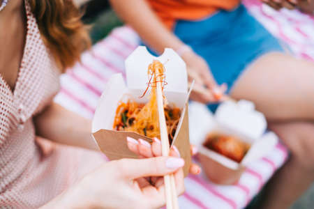 Friends eating street food outdoor on the park, enjoying summer weather.の写真素材