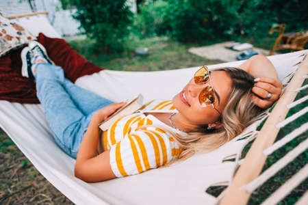 Young woman relaxing in hammock outdoors, in the backyard garden. Enjoying summerの写真素材