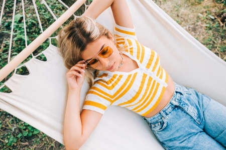Young woman relaxing in hammock outdoors, in the backyard garden. Enjoying summerの写真素材