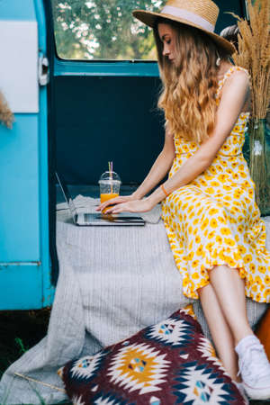 Young caucasian woman using laptop computer while sitting oa van outdoors.
