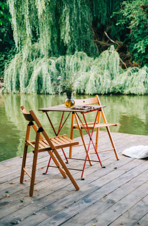 Table with chairs on a wooden pier on a lake, nobody.の写真素材