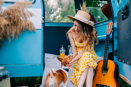 Portrait of cheerful young woman with her dog outdoors near van, simmer traveling concept.の写真素材