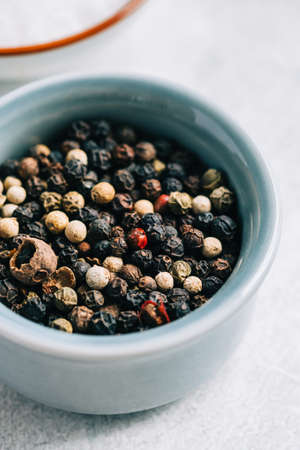 Peppercorns mix in small bowl with salt on the table, close-up.の写真素材