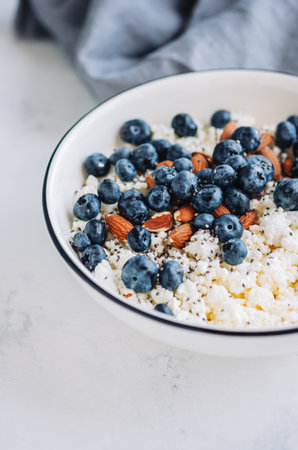 Crumbly curd with blueberries, almonds and chia seeds in white bowl on the table.の写真素材