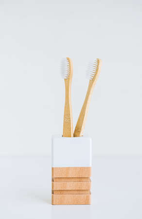 Bamboo toothbrushes in a wooden cup making with natural materials, isolated on white backgroundの写真素材