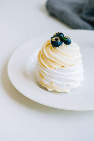 Dessert Anna Pavlova with meringue and cheese cream inside, decorated with blueberries on tableの写真素材