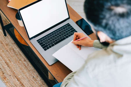 Caucasian man college student, studying with laptop distantly preparing for test exam writing essay doing homework at home, distantly education concept.の写真素材