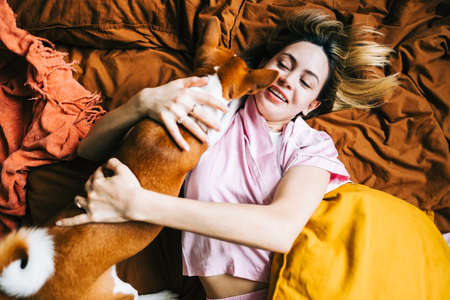 Young caucasian happy woman waking up with pet in the morning.