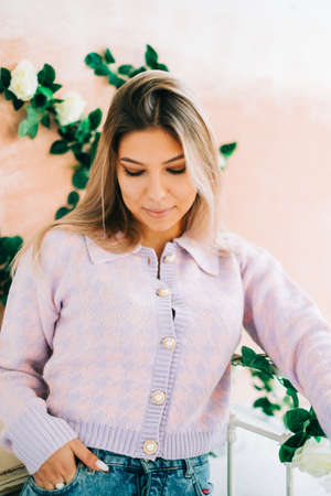 Portrait of attractive caucasian woman standing in a cozy bright bedroom, with flowers on a wall