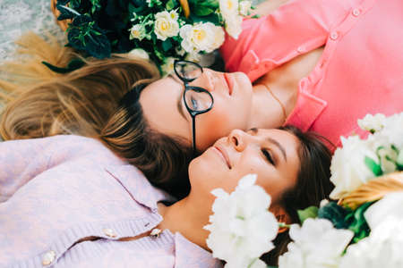 Portrait of two attractive caucasian woman lying on a floor with flowers. femininity conceptの写真素材