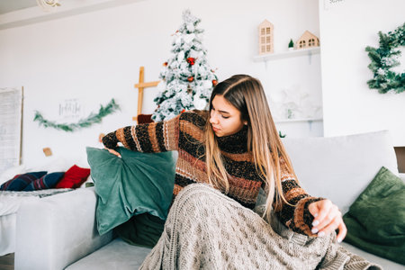 Young caucasian woman relaxing on a sofa at home in christmas holidays.の写真素材