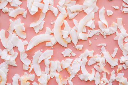 Dried coconut chips on pink background.