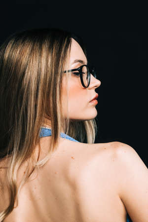Back view portrait of a young blond woman posing isolated over black background.の写真素材