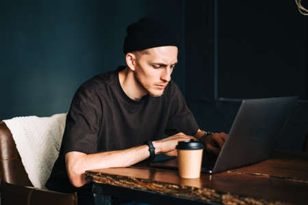 Young man mobile developer writes program code on a computer, programmer work in home office.の写真素材