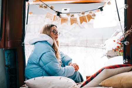 Portrait of young caucasian woman sitting in a car in winter day, during traveling on a van and...
