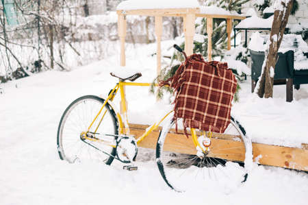 Snow covered bike in the backyard with a knitted plaid.の写真素材