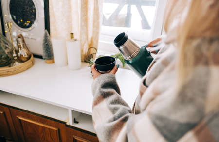 Young woman pouring hot tea in a cup in the morning.の写真素材