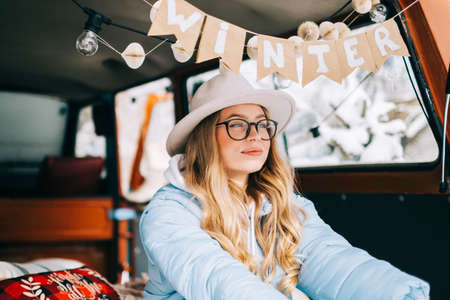 Portrait of young caucasian happy woman sitting in a car on sunny winter day, during traveling on a van and enjoying holiday.の写真素材