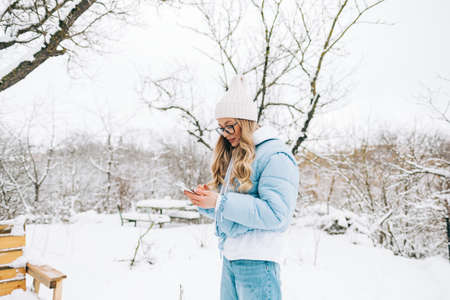 Young caucasian woman using mobile phone outdoor on the backyard in winter time.の写真素材