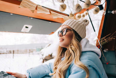 Portrait of young caucasian happy woman sitting in a car in winter day, during traveling on a van and enjoying holiday.の写真素材