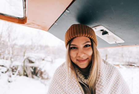 Portrait of a cheerful young woman standing outdoor near van in winter time.の写真素材