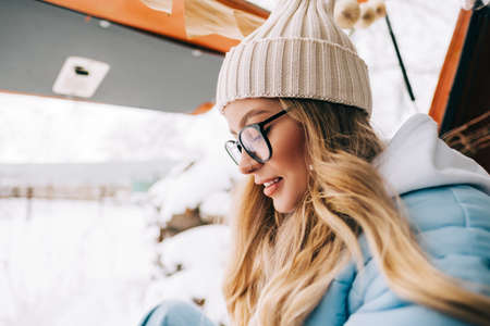 Portrait of young caucasian happy woman sitting in a car in winter day, during traveling on a van...
