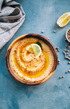 Fresh hummus in wooden plate with lemon, vegetarian food. top viewの写真素材