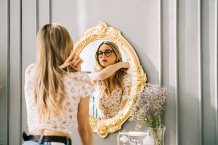 Young attractive caucasian woman looking in the mirror at her face, beauty treatment, skin care concept.の写真素材