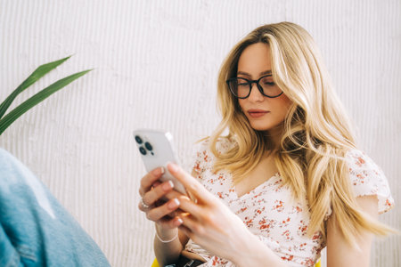 Young attractive woman sitting on a chair and using mobile phone.の写真素材