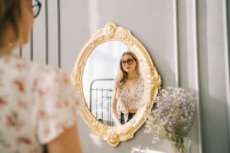 Young attractive caucasian woman looking in the mirror at her face, beauty treatment, skin care concept.の写真素材