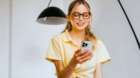 Portrait of happy attractive woman enjoy success on mobile phone at home . Joyful girl reading good news on smartphone.の写真素材