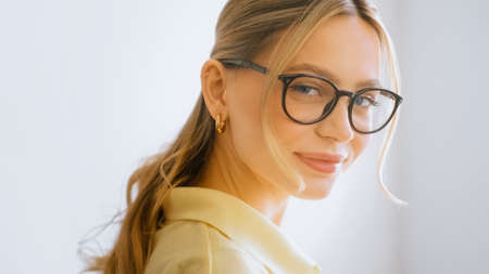 Portrait of happy smiling young attractive caucasian woman in eyeglasses looking on camera.の写真素材