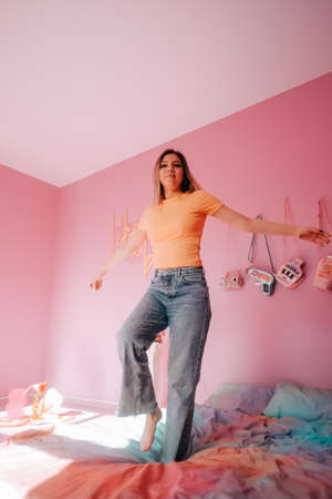 Portrait of young attractive caucasian cheerful woman relaxing in cozy trendy bedroom with pink wall.の写真素材