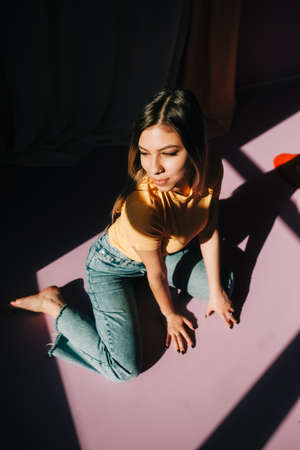 Portrait of young attractive caucasian woman sitting on a floor in a bedroom in sunlight.の写真素材