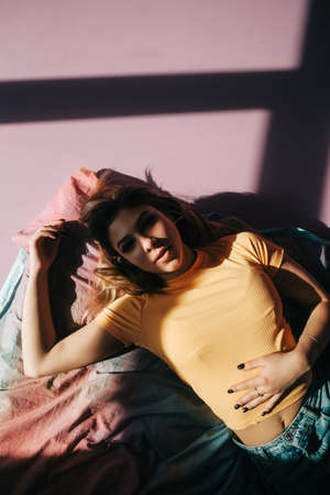 Young attractive caucasian woman relaxing on a bed in sunlight.の写真素材