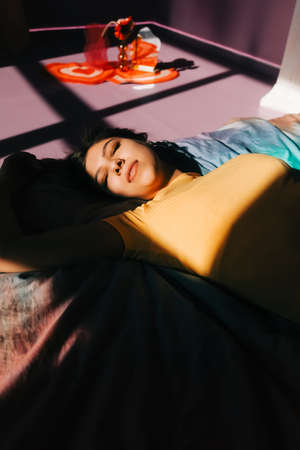 Young attractive caucasian woman relaxing on a bed in sunlight.の写真素材