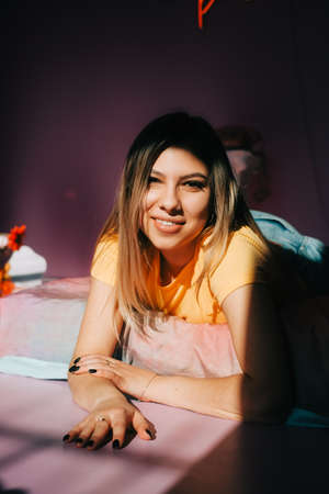 Young attractive caucasian woman relaxing on a bed in sunlight.の写真素材