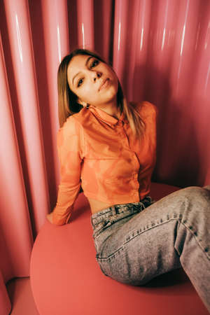 Young stylish attractive caucasian woman posing in a room with pink walls.の写真素材