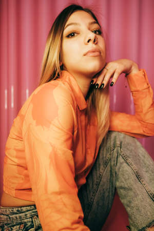 Young stylish attractive caucasian woman posing in a room with pink walls.の写真素材